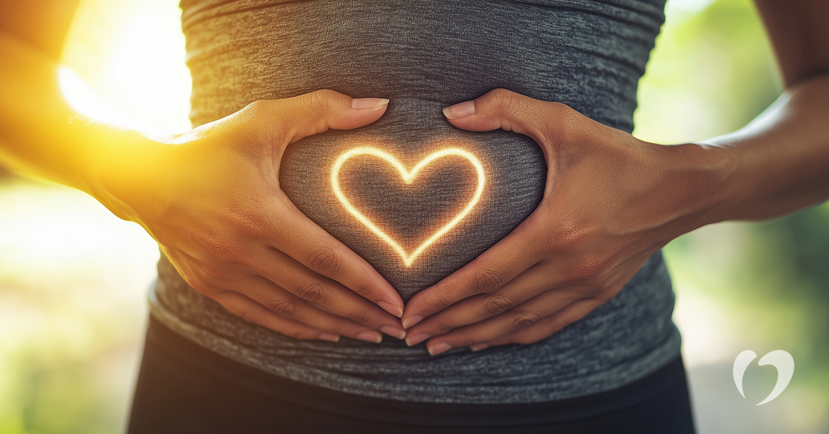 woman forming a heart with her hands over her stomach
